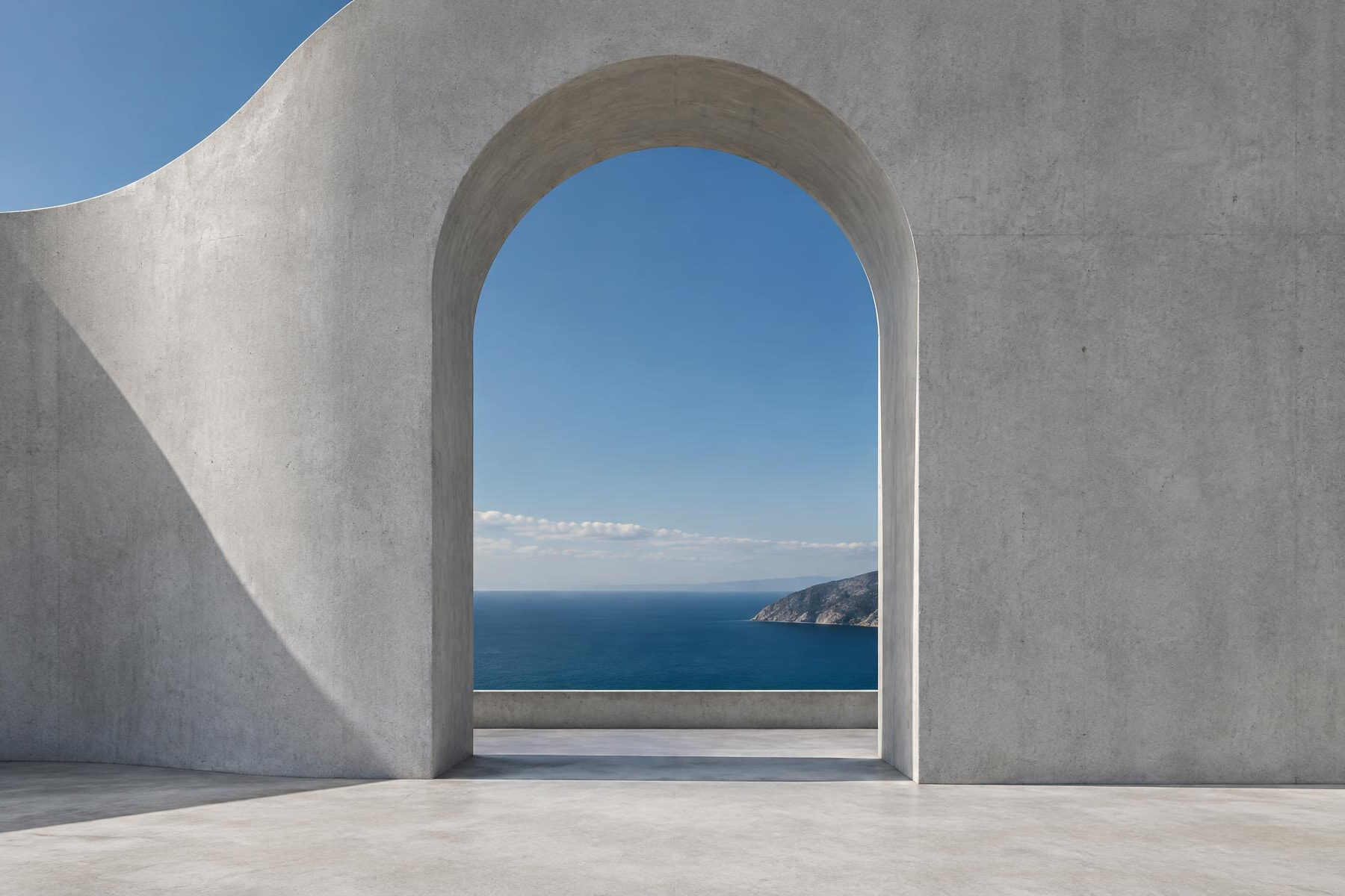 Arco de concreto claro emoldurando o céu e o mar azul.